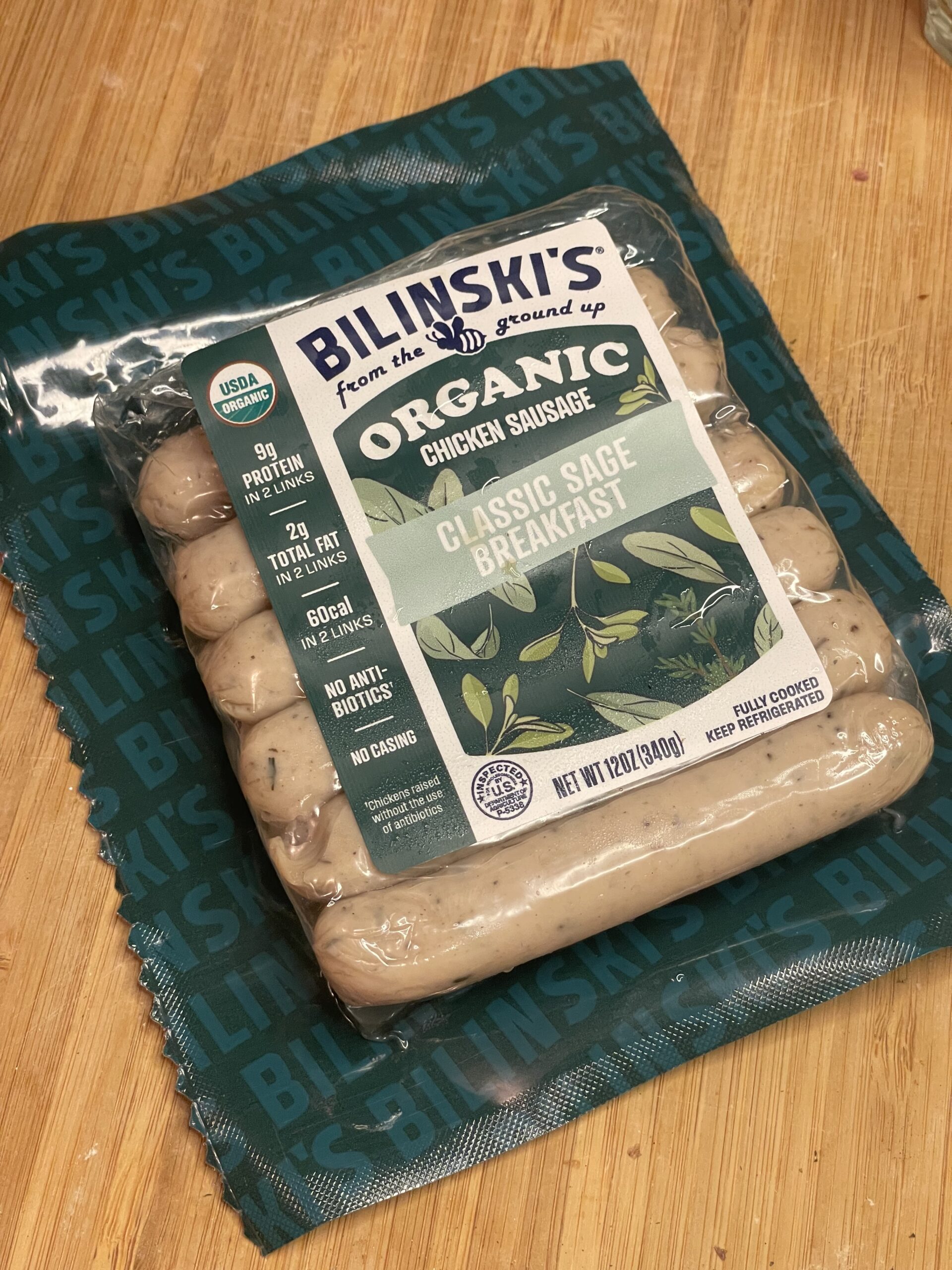 Package of Bilinski’s Organic Classic Sage Chicken Sausage resting on branded green paper, highlighting its clean, preservative-free label and pasture-raised ingredients.