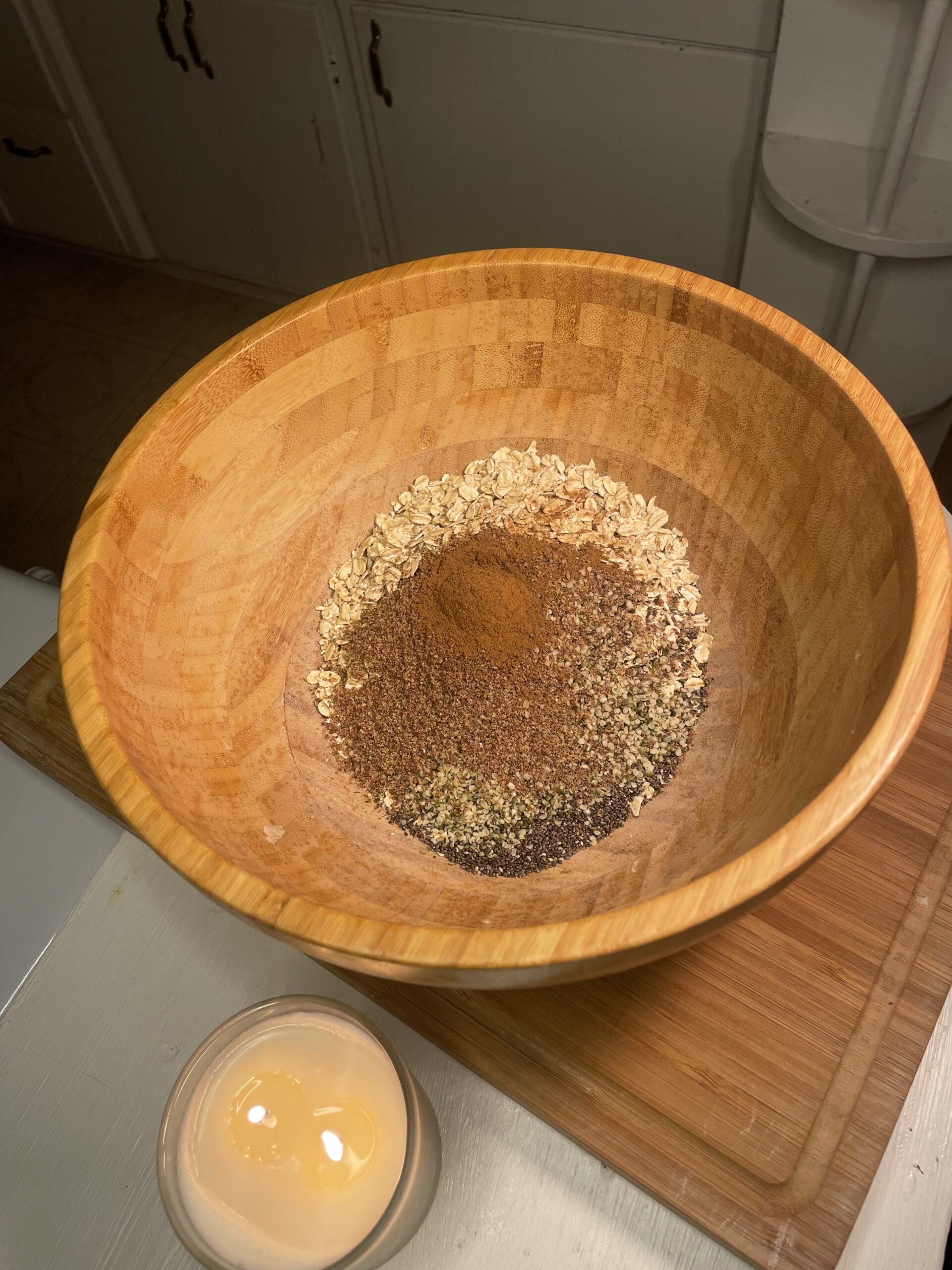 Dry ingredients including oats, flaxseed, chia seeds, and cinnamon in a wooden mixing bowl for granola prep.