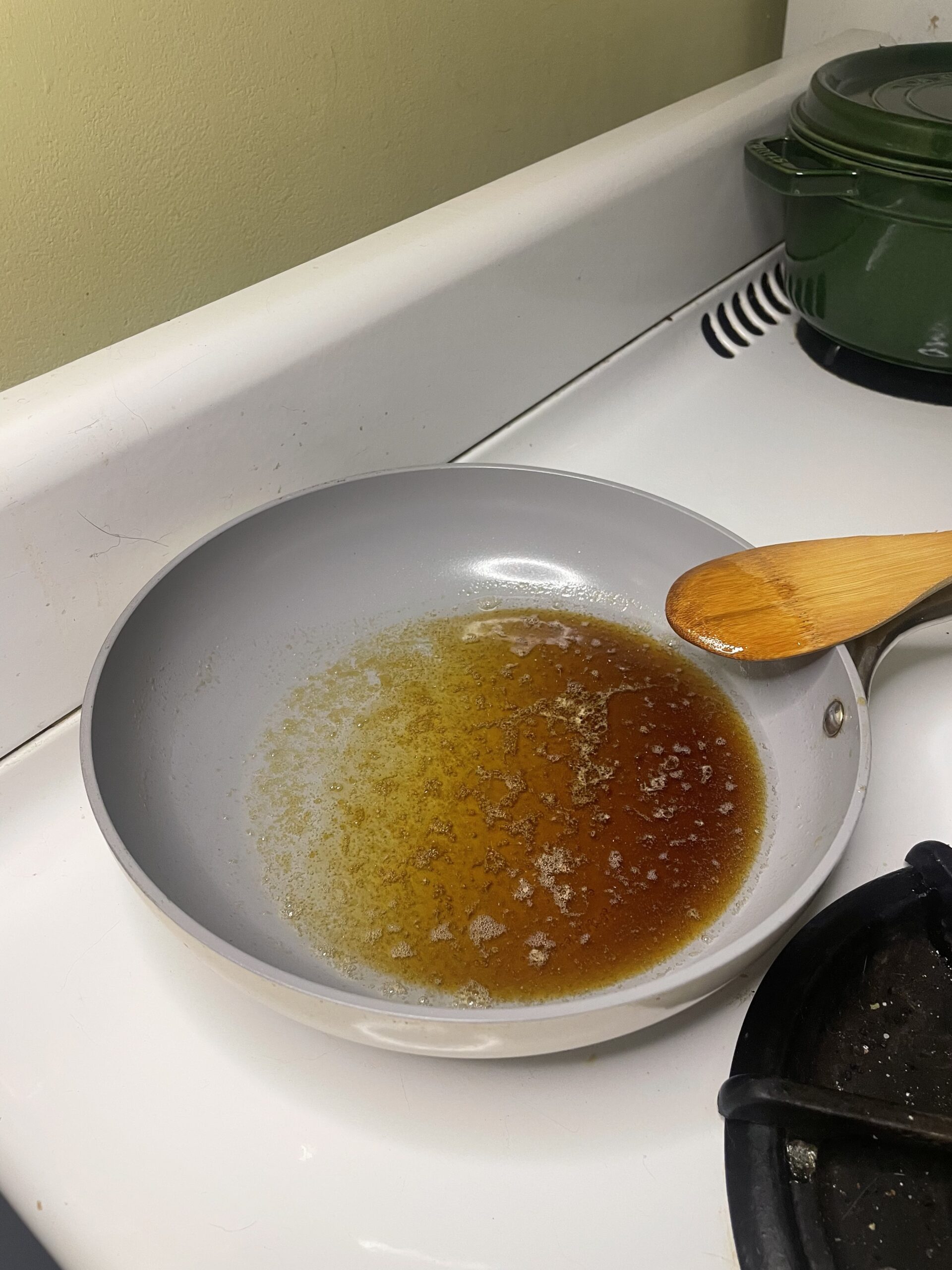 Butter and maple syrup melting in a ceramic nonstick skillet for granola sweetener base.