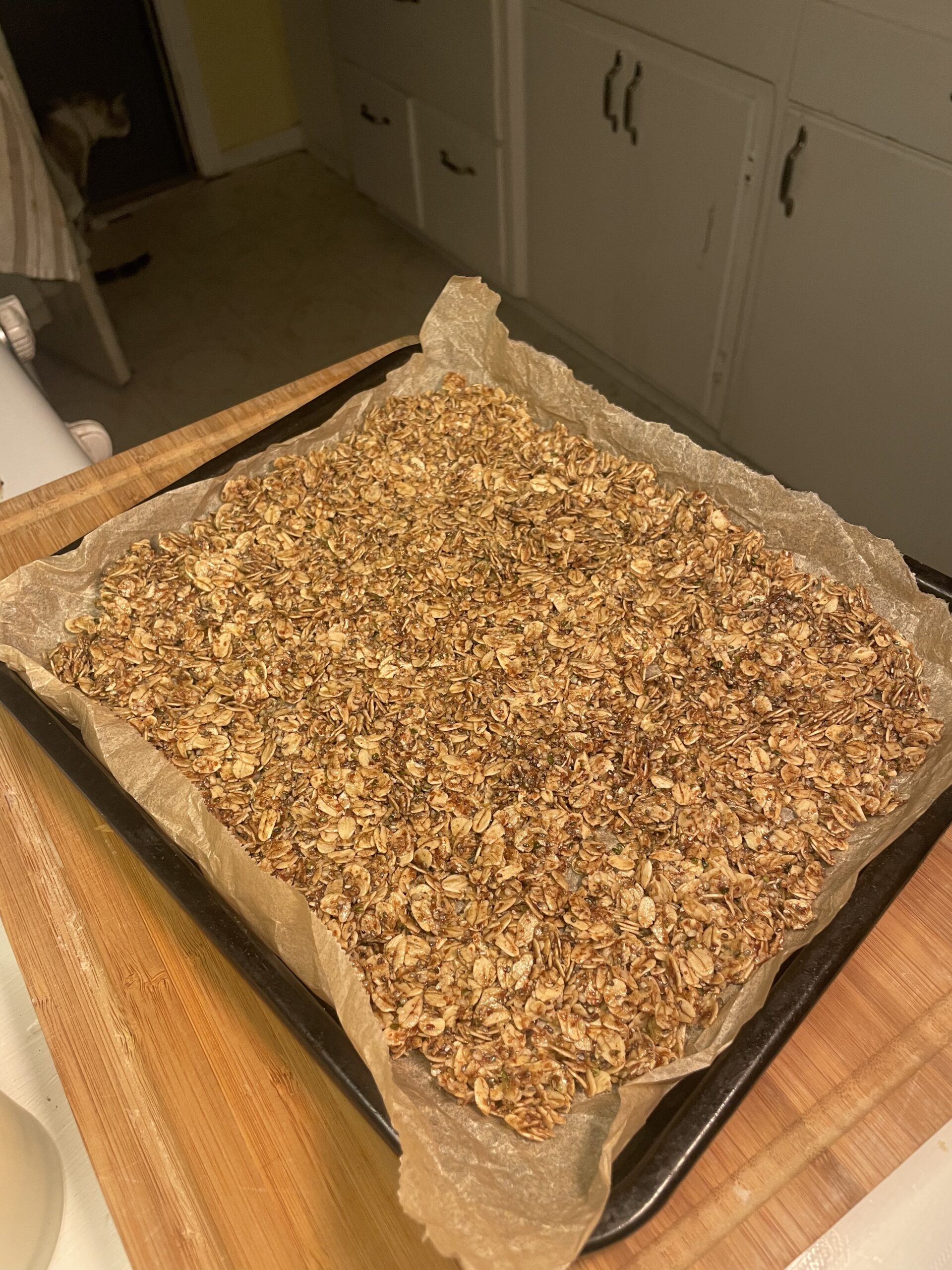 Sheet of golden brown homemade maple seeded granola cooling on baking parchment.