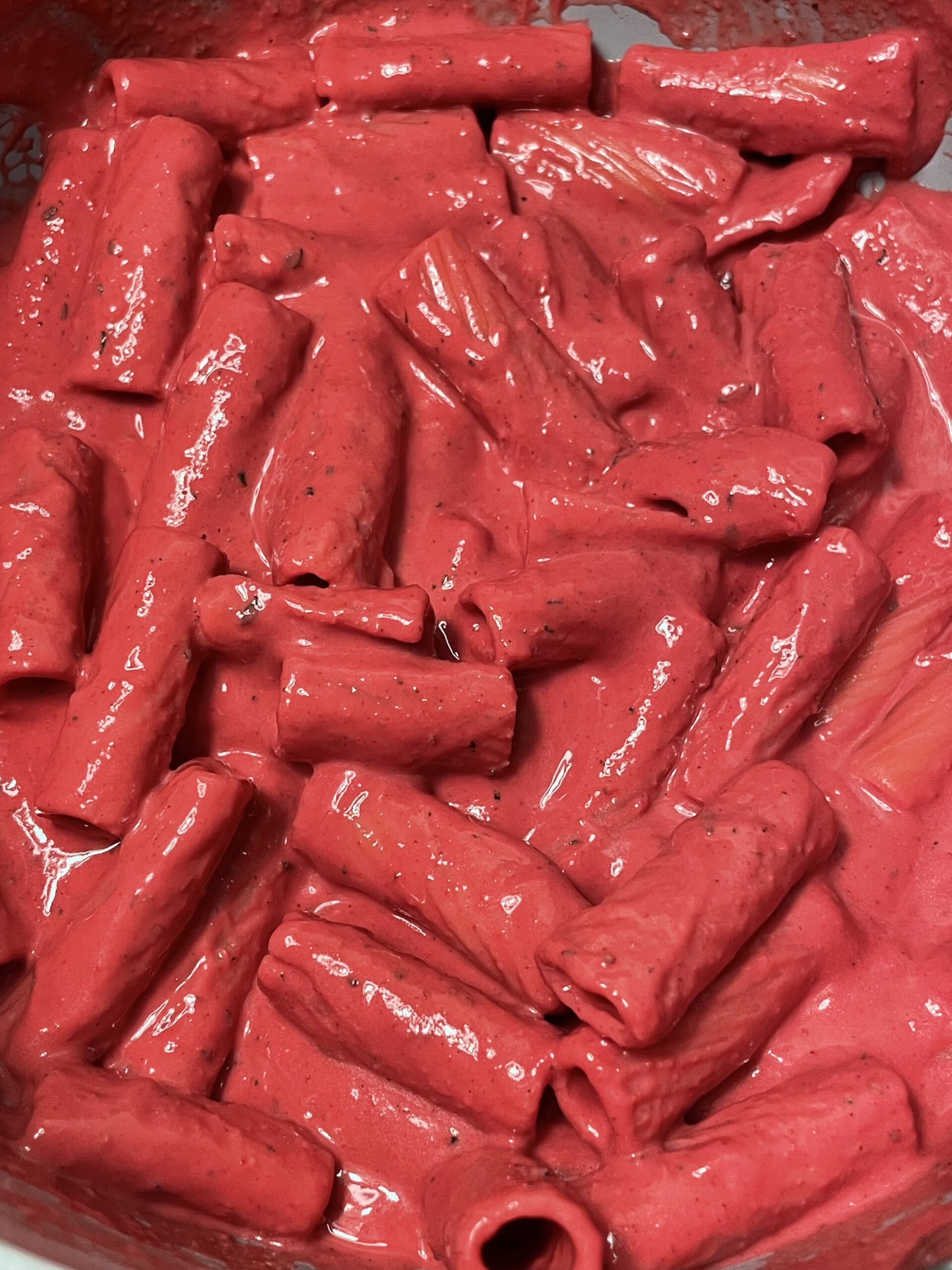 Freshly cooked pasta generously coated in creamy, vibrant pink sauce, ready to be plated.