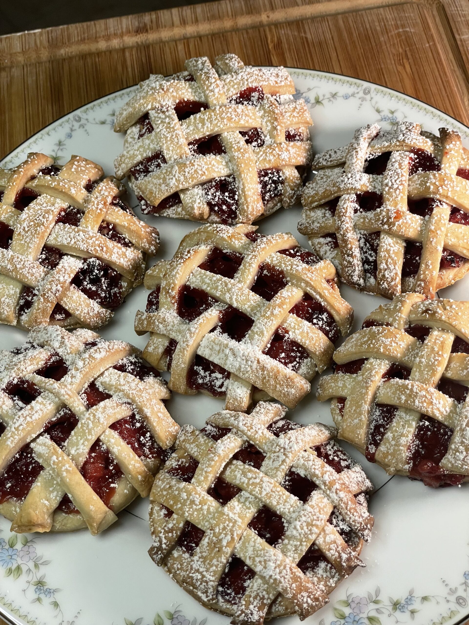 Detailed view of the flaky lattice crust on baked strawberry lavender hand pies, showing crisp texture and powdered sugar finish.