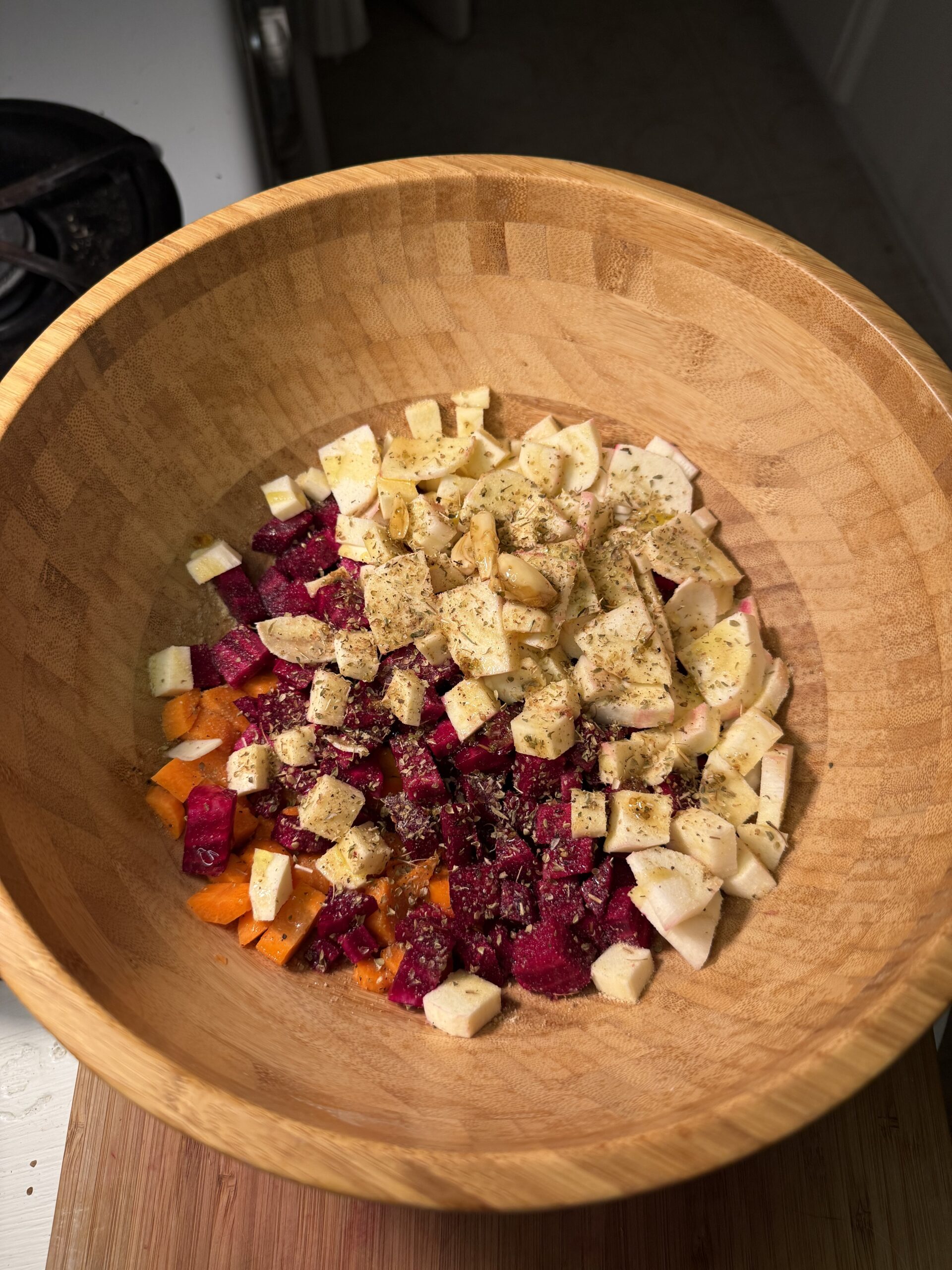 In a large wooden bowl, cut carrots, cut beets, and cut parsnips are seasoned. 
